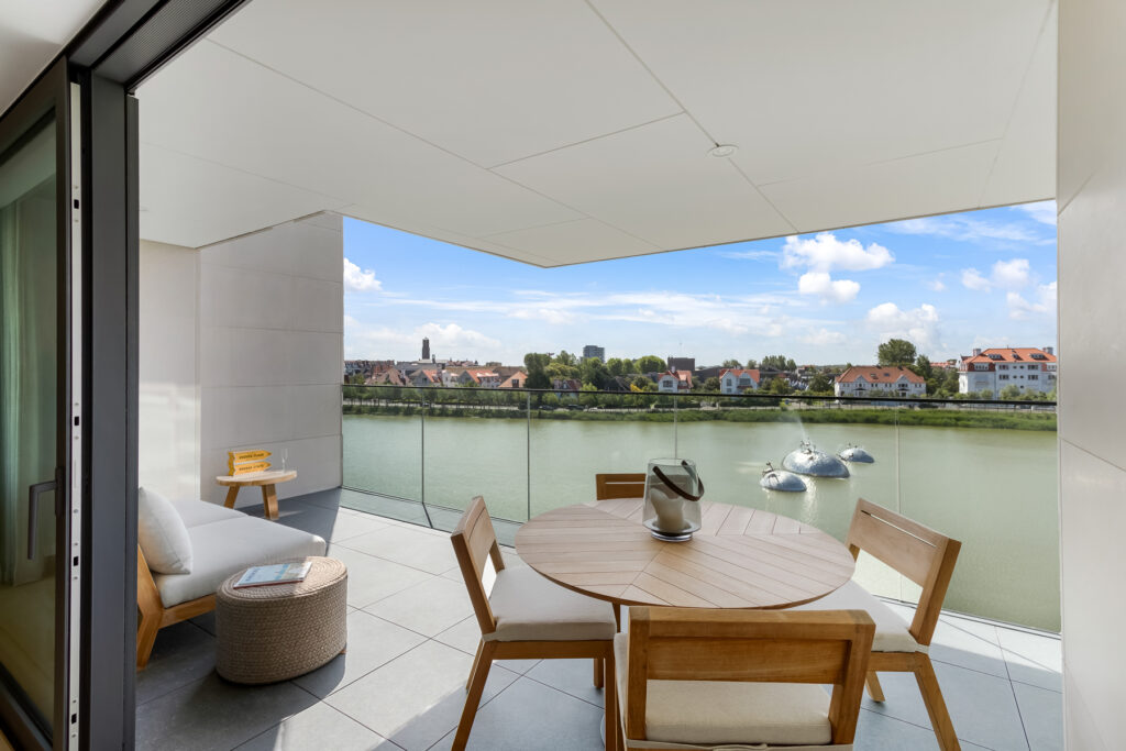 Interieurfotografie van een uitzicht vanaf een luxe balkon in Knokke, met uitzicht op de Zegemeer en het kunstwerk "Waving Crabs" van Panamarenko.