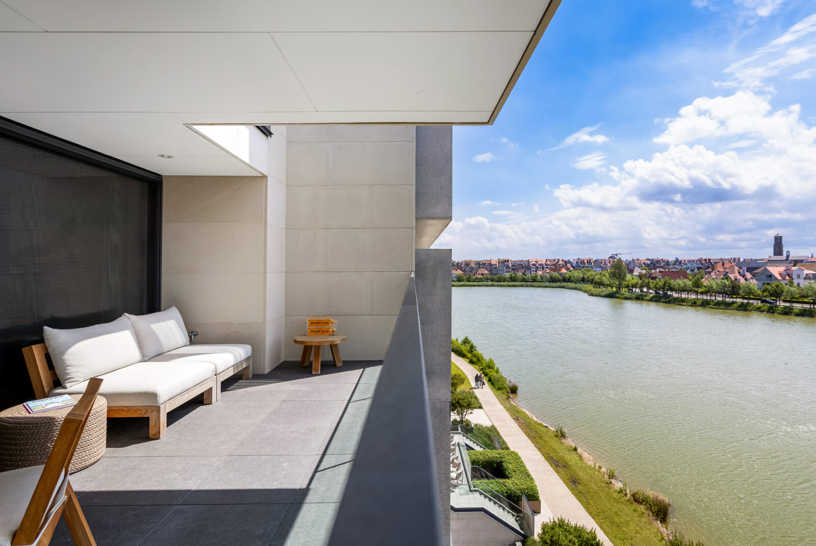 Luxe balkon met ligbed en zitruimte, badend in natuurlijk licht, met panoramisch uitzicht op het Zegemeer in Knokke.