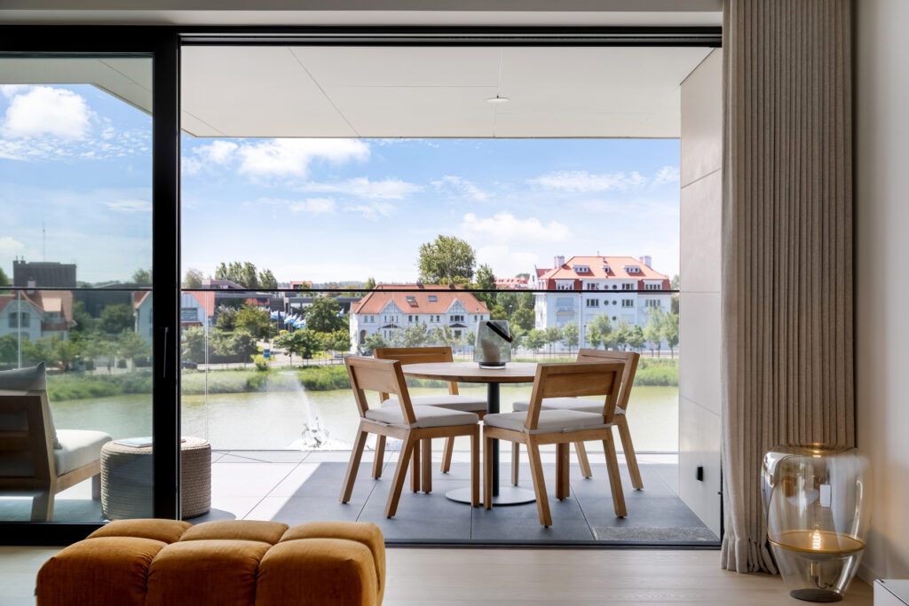 Interieurfotografie van moderne eetruimte met uitzicht op de Zegemeer en de Waving Crabs fontein in Knokke, gefotografeerd vanaf een ruim balkon.