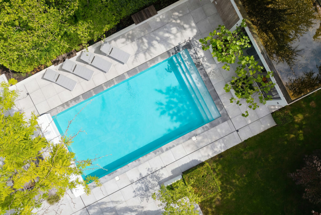 dronefotografie van een bovenaanzicht van een zwembad met vier ligstoelen en een poolhouse